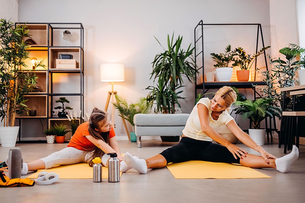 Mother and daughter doing fitness exercises in living room at home